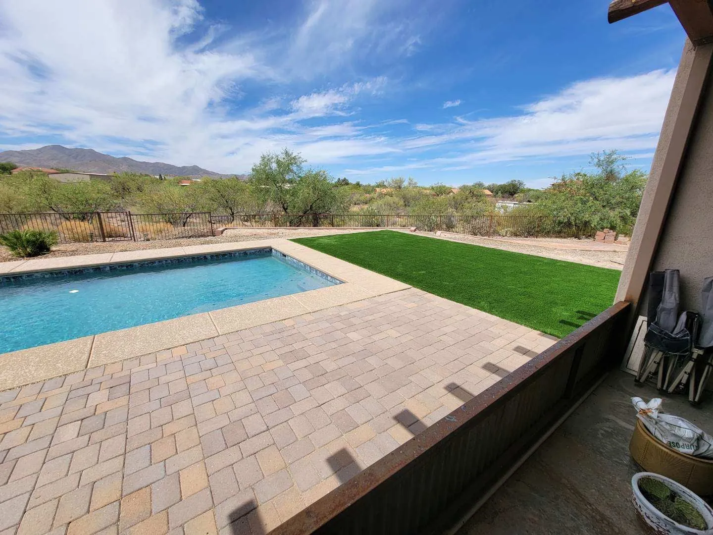 Paver surface beside a pool and artificial turf